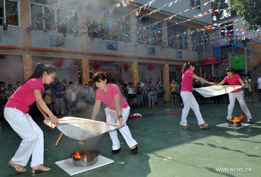 Teachers take part in a drill to use fire fighting blanket in a kindergarten in Huaiyin District of Jinan, capital of east China's Shandong Province, June 14, 2013. Kindergartens in Huaiyin District held emergent fire fighting drills on Friday, in an aim to improve children and staff's ability to prevent fires, save themselves and cooperate with others. (Xinhua/Zhu Zheng) 