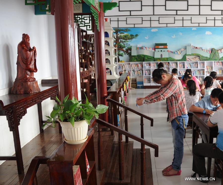 A girl worships a sculpture of Confucius before she starts reading books at Shuangqiao Primary School in Pingquan County, north China's Hebei Province, June 14, 2013. Learning Chinese classics, like the Three-Character Classic and the Analects of Confucius, for one class hour per week has been part of the curriculum for students in Shuangqiao Primary School since 2009. (Xinhua/Wang Xiao) 