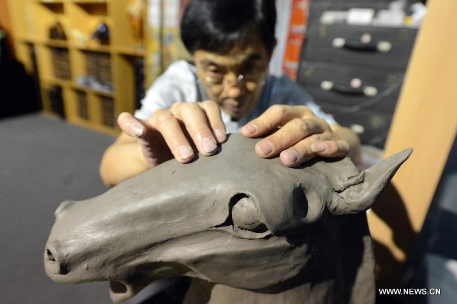 An artist demonstrates the making of a tri-colored glazed pottery horse of the Tang Dynasty (618-907) at the 4th International Festival of Intangible Cultural Heritage in Chengdu, capital of southwest China's Sichuan Province, June 15, 2013. The nine-day festival kicked off here on Saturday. (Xinhua/Li Xiangyu)