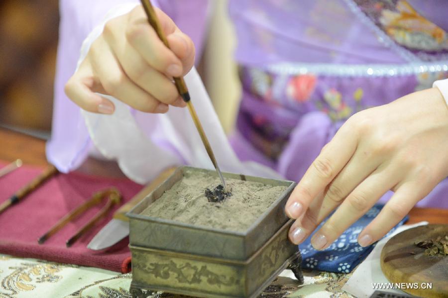 An artist makes Guan Spice, a famous spice originated in Dongguan of south China's Guangdong Province, at the 4th International Festival of Intangible Cultural Heritage in Chengdu, capital of southwest China's Sichuan Province, June 15, 2013. The nine-day festival kicked off here on Saturday. (Xinhua/Li Xiangyu)