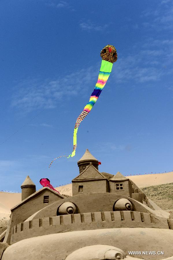 A kite flies over an artwork of sand sculpture during a tourism promotion event held at the scenery spot of the Qinghai Lake in northwest China's Qinghai Province, June 15, 2013. (Xinhua/Zhang Hongxiang) 