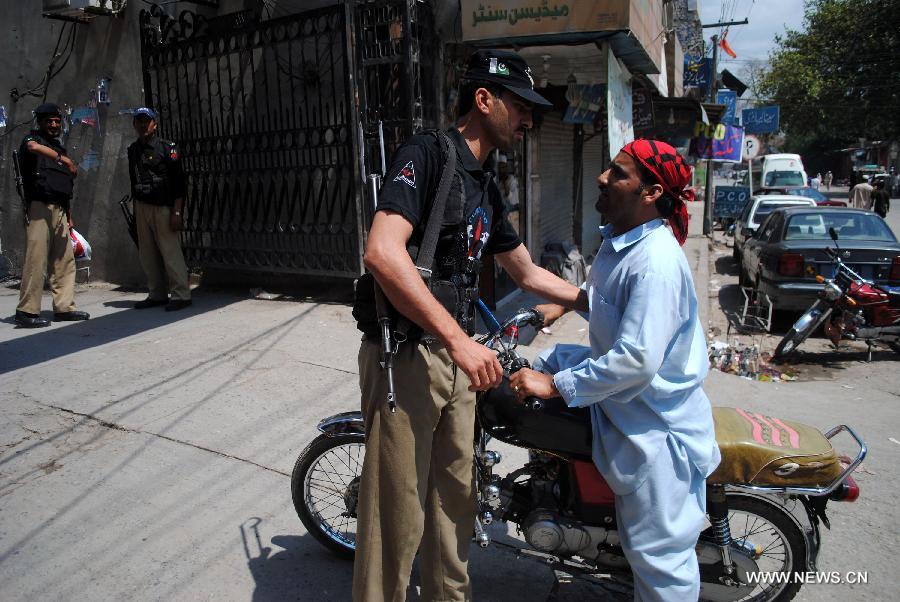 A Pakistani policeman checks a motorbike rider outside Lady Reading Hospital (LRH) in northwest Pakistan's Peshawar, on June 16, 2013. At least 20 people were killed and 27 others injured in a twin bomb attack followed by firing in Pakistan's southwest city of Quetta on Saturday, said police. (Xinhua/Umar Qayyum)  