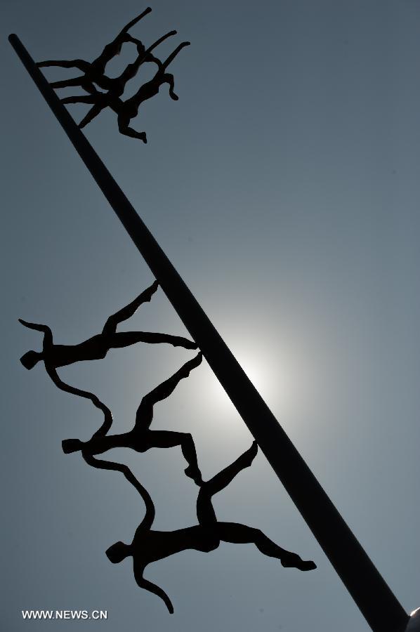 A city statue is silhouetted under the sun in southwest China's Chongqing Municipality, June 17, 2013. The highest temperature in Chongqing reached 39 degrees centigrade here on Monday. (Xinhua/Chen Cheng)