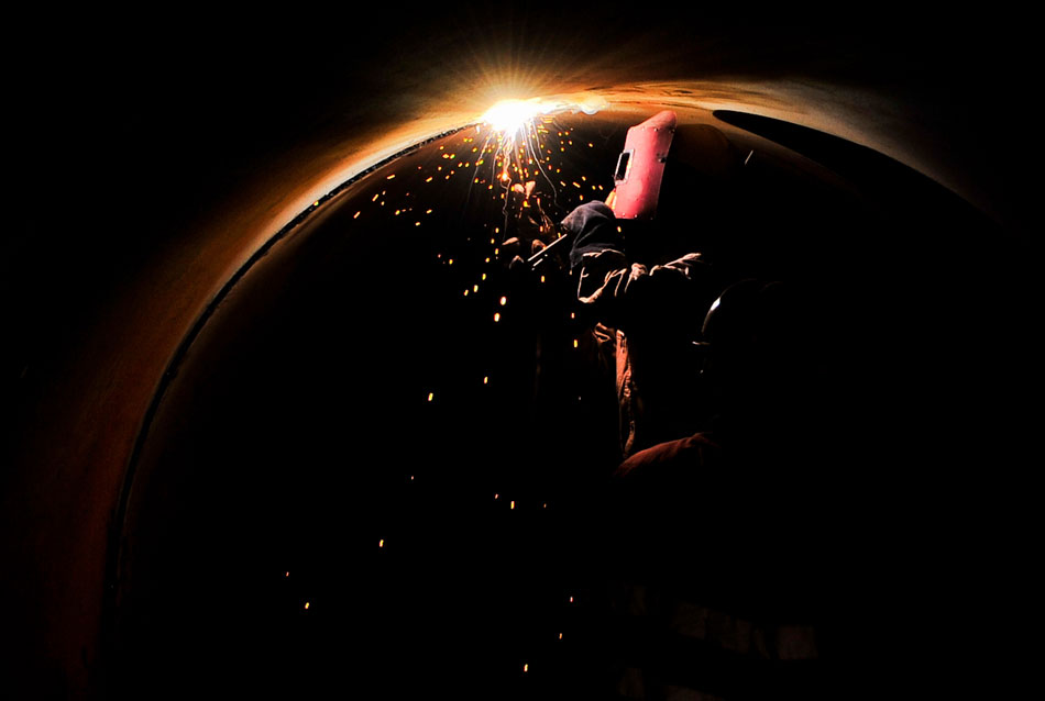 A worker welds inside a pipeline used in a water supply project for Tianjian’s Binhai New Area, June 13, 2013. (Xinhua/Zhang Chaoqun)