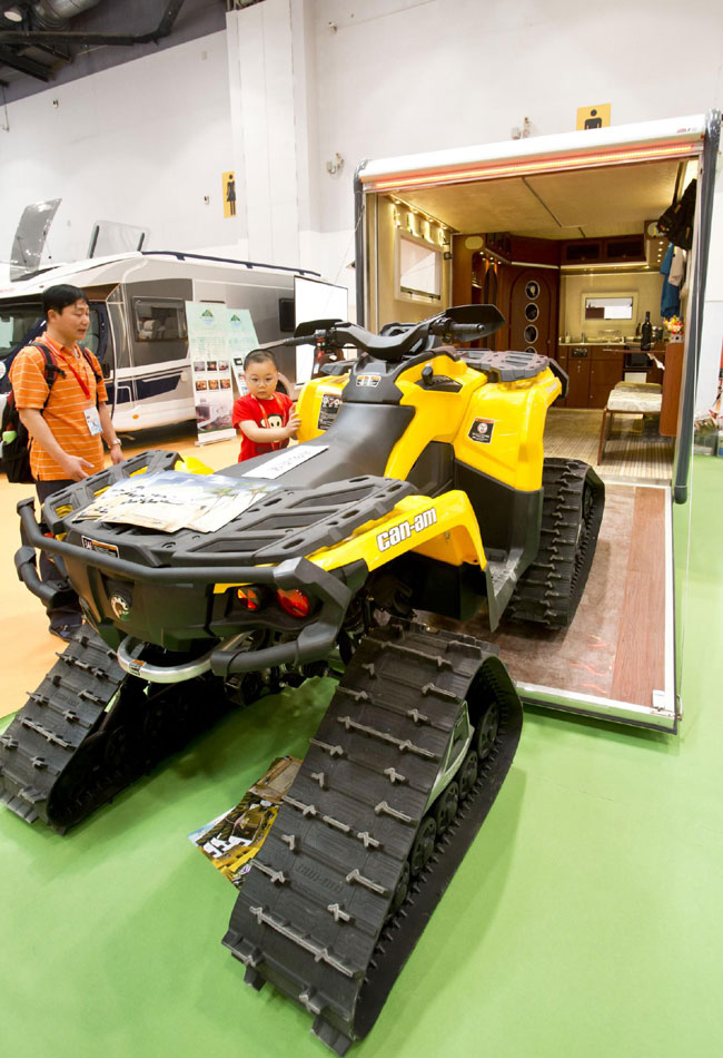 Visitors look at a camper van that can carry an all-terrain motorcycle at the 'All in Tuning All in Caravanning' Show China 2013 on June 15, 2013, at the China National Convention Center, Beijing. [Photo / Xinhua]