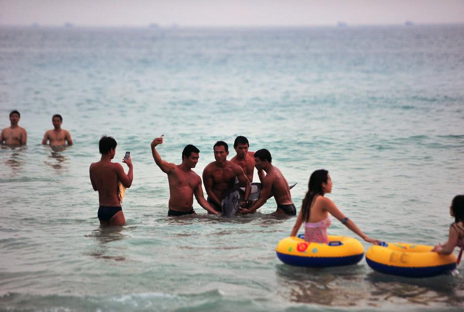 Photos showing the men lifting and posing with the dolphin.(Photo/ Guangming Online)