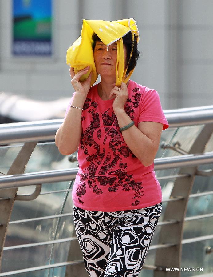 A woman holds a bag as a shelter while walking on a street in Shanghai, east China, June 17, 2013. The highest temperature in Shanghai reached 36 degrees centigrade on June 17. (Xinhua/Ding Ting) 