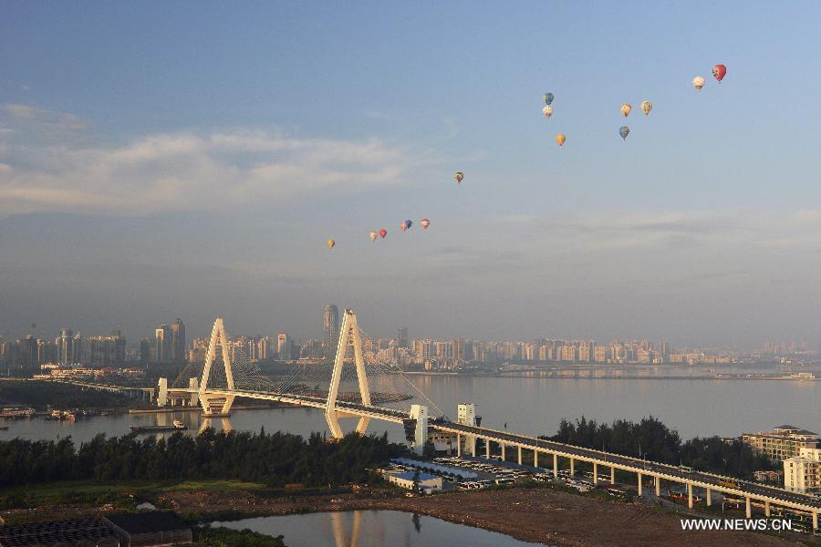 Hot air balloons fly over the Millenium Bridge during the 7th Hot Air Balloon Festival and 2013 H1 China Hot Air Balloon Challenge in Haikou, capital of southernmost China's Hainan Province, June 18, 2013. 15 hot air balloons participated in the event Tuesday to to fly across the Qiongzhou Strait from the city of Haikou and reach a designated place in neighboring Guangdong Province. (Xinhua/Jiang Jurong)