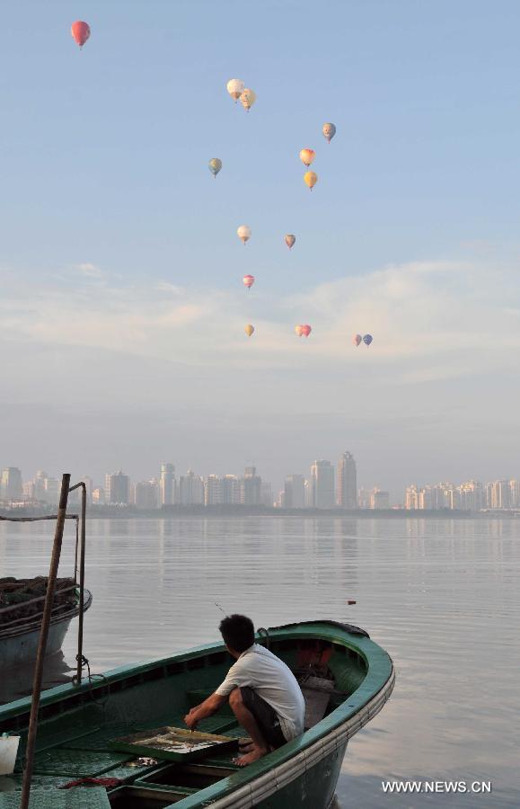 Hot air balloons fly over the city zone during the 7th Hot Air Balloon Festival and 2013 H1 China Hot Air Balloon Challenge in Haikou, capital of southernmost China's Hainan Province, June 18, 2013. 15 hot air balloons participated in the event Tuesday to to fly across the Qiongzhou Strait from the city of Haikou and reach a designated place in neighboring Guangdong Province. (Xinhua/Pan Huaqing)