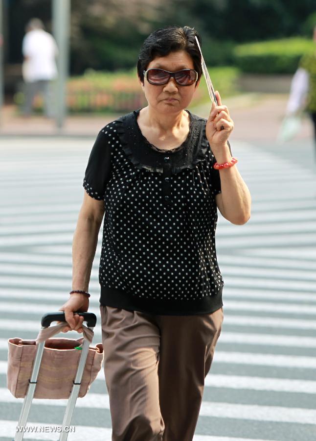 A citizen holds a fan for shelter while walking in Shanghai, east China, June 18, 2013. The highest temperature in Shanghai reached 37 degrees centigrade on June 18. (Xinhua/Ding Ting) 