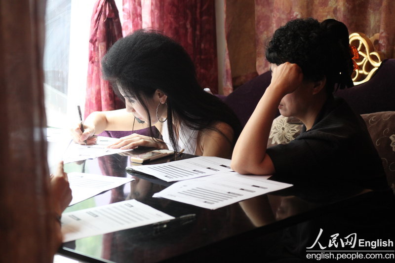 Candidates fill in forms prior to a so-called "rich blind date" held in Jinan, capital city of east China's Shandong province, June 16, 2013. Fifty candidates taking part in the "rich blind date" will be selected to attend a party for rich individuals to be held overseas in July. (Photo by Pan Yongqiang/ CFP)