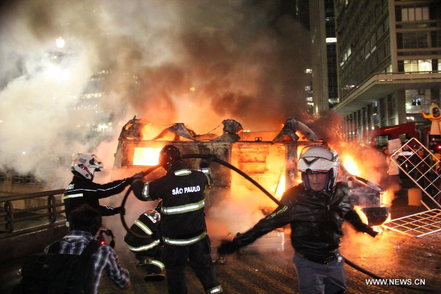 Members of emergency teams try to extinguish fire on a vehicle of a television station, during a protest against price increase of public transport, and the millionaire Brazilian government spending for the FIFA Confederations Cup Brazil 2013 and World Cup Brazil 2014, in Sao Paulo, Brazil, on June 18, 2013. (Xinhua/Edison Temoteo/Futurapress/Agencia Estado) 