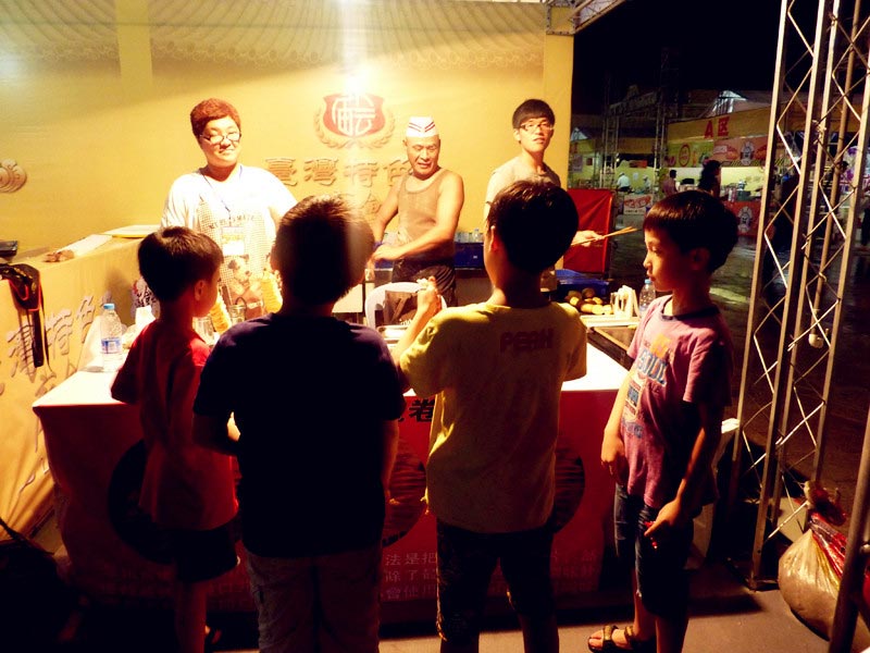 Four young boys stand in front of a Taiwanese snack stand at the Taiwan Characteristics Temple Fair in Xiamen, southeast China's Fujian Province, on Friday, June 14, 2013. The temple fair is part of the city's fifth Straits Forum to be held on June 15-21. Vendors are selling food, specialties and creative products from Taiwan at the temple fair. (CRIENGLISH.com/Yang Yong)