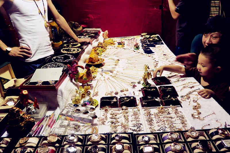 A small boy is attracted to a jewelry stand at the Taiwan Characteristics Temple Fair in Xiamen, southeast China's Fujian Province, on Friday, June 14, 2013. The temple fair is part of the city's fifth Straits Forum to be held on June 15-21. Vendors are selling food, specialties and creative products from Taiwan at the temple fair. (CRIENGLISH.com/Yang Yong)