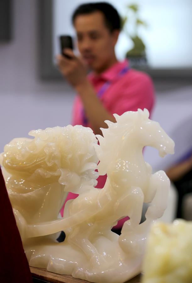 A man takes photos of jade carving works during the 2nd China (Tianjin) International Stone Blocks, Products & Equipment Exposition in Tianjin, north China, June 18, 2013. The exposition, opened here on Tuesday, has attracted more than 800 related enterprises both at home and abroad.(Xinhua/Wang Qingyan) 