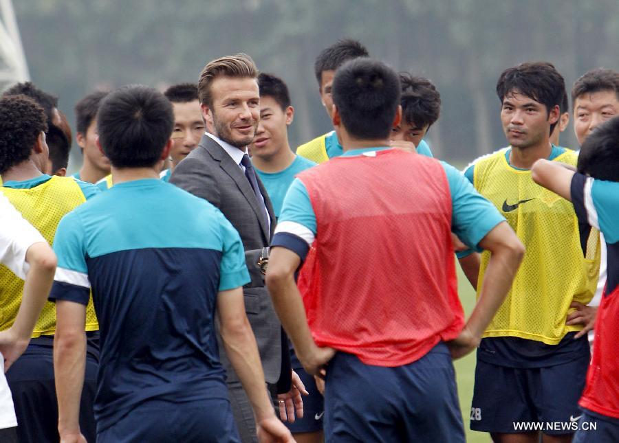 Recently retired football player David Beckham talks with players from Shanghai Shenxin Football club in Shanghai, east China, June 19, 2013. David Beckham is on a seven-day visit to China as the ambassador for the Football Programme in China and China's Super League. (Xinhua/Fan Jun)