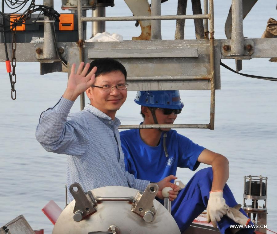 Qiu Jianwen, a professor from Hong Kong Baptist University, waves at the exit of China's manned deep-sea submersible Jiaolong after a sample-capture mission in the cold vents of south China sea, south China, June 19, 2013. Qiu obtained deep-sea samples in the cold vents of the South China Sea during a dive conducted on Wednesday. (Xinhua/Zhang Xudong)