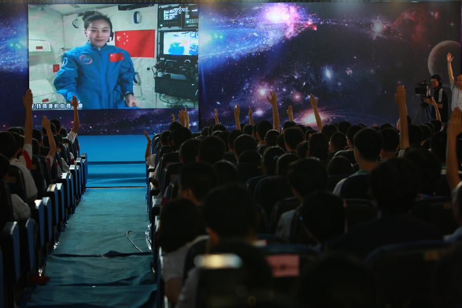 Students raise their hands to ask questions to the female astronaut Wang Yaping, one of the three crew members of Shenzhou-10 spacecraft, at the High School Affiliated to Renmin University of China, in Beijing, capital of China, June 20, 2013. A special lecture began Thursday morning, given by Wang Yaping aboard China's space module Tiangong-1 to students on Earth. (Xinhua/Wang Yongzhuo)