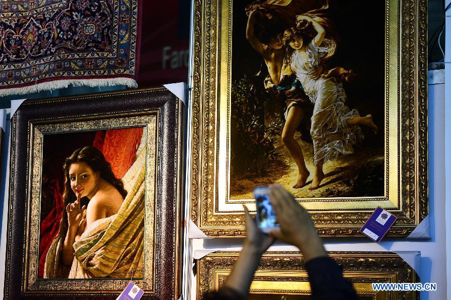 A visitor takes a photo of decorational carpets at a Tibetan carpet exposition in Xining, capital of northwest China's Qinghai Province, June 20, 2013. Opened Thursday, the exposition attracted some 110 exhibitors from 9 countries. (Xinhua/Wu Gang)