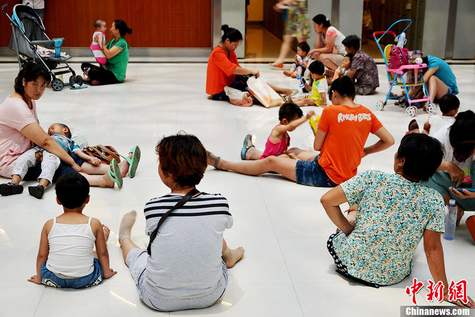 People enjoy the cool air provided in a shopping mall in Xuchang, central China's Henan province on June 17, 2013. The temperature of the city reached 39 degrees Celsius on the day. (Photo/Chinanews)