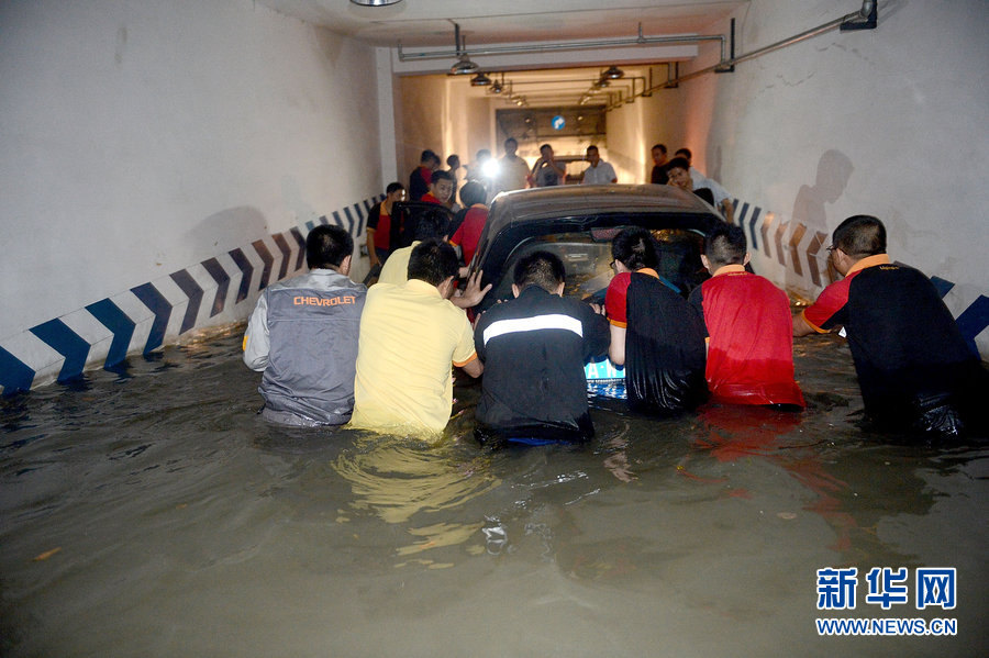 People push flooded cars out of a garage in Chengdu, Southwest China's Sichuan province on June 20, 2013.