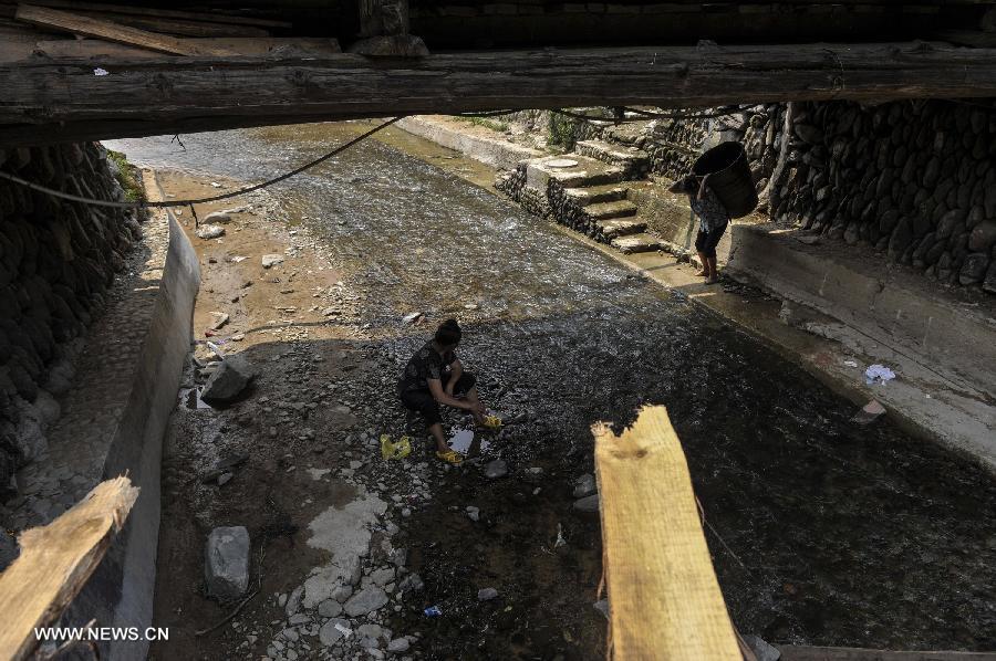 People rest at a wind and rain bridge of Zhaoxing Dong Village in Liping County, southwest China's Guizhou Province, June 20, 2013. Zhaoxing Dong Village is one of the largest Dong village in Guizhou. In 2005, it was ranked one of China's six most beautiful villages and towns by Chinese National Geography. (Xinhua/Ou Dongxu) 