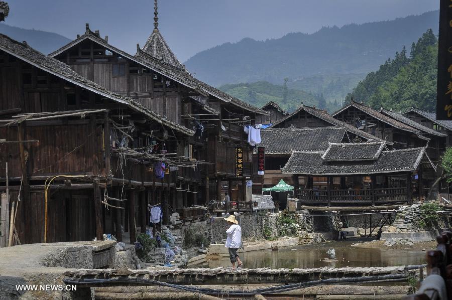 A man walks on a bridge at Zhaoxing Dong Village in Liping County, southwest China's Guizhou Province, June 20, 2013. Zhaoxing Dong Village is one of the largest Dong village in Guizhou. In 2005, it was ranked one of China's six most beautiful villages and towns by Chinese National Geography. (Xinhua/Ou Dongxu)