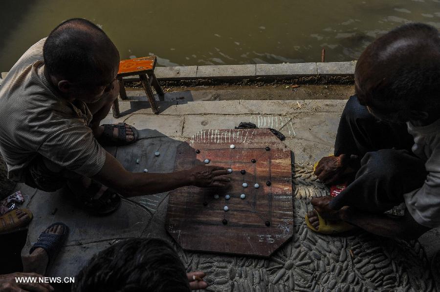 People play chess near a brook at Zhaoxing Dong Village in Liping County, southwest China's Guizhou Province, June 20, 2013. Zhaoxing Dong Village is one of the largest Dong village in Guizhou. In 2005, it was ranked one of China's six most beautiful villages and towns by Chinese National Geography. (Xinhua/Ou Dongxu)