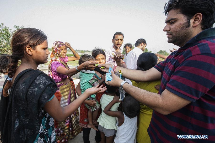 A man (R)delivers food to homeless people near the Yamuna River in New Delhi, India, June 20, 2013. The Indian capital has been put on flood alert after its main Yamuna river breached the danger mark following incessant rainfall since June 16. So far, more than 150 people have died in Uttarakhand floods, while thousands have been displaced and stranded, according to reports. (Xinhua/Zheng Huansong) 