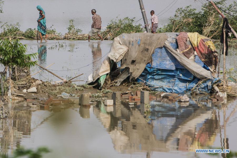 People walk past flooded gutter houses near the Yamuna River in New Delhi, India, June 20, 2013. The Indian capital has been put on flood alert after its main Yamuna river breached the danger mark following incessant rainfall since June 16. So far, more than 150 people have died in Uttarakhand floods, while thousands have been displaced and stranded, according to reports. (Xinhua/Zheng Huansong) 