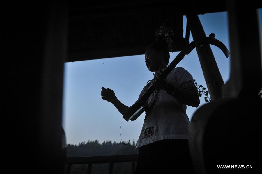A woman plays the Chinese lute in Dimen Dong minority village in Liping County of southwest China's Guizhou Province, June 20, 2013. Dimen is a Dong minority village with about 2,500 villagers. It is protected properly and all the villagers could enjoy their peaceful and quiet rural life as they did in the past over 700 years. (Xinhua/Ou Dongqu)