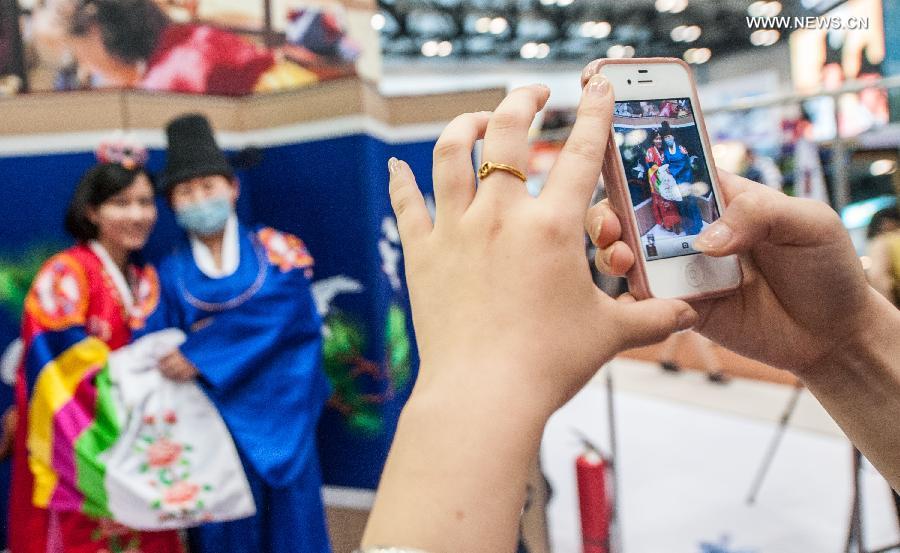 Visitors wearing traditional Korean costumes pose for photo at the Beijing International Tourism Expo (BITE) 2013 in Beijing, capital of China, June 21, 2013. The BITE 2013 kicked off on Friday, attracting 887 exhibitors from 81 countries and regions. (Xinhua/Zhang Yu)