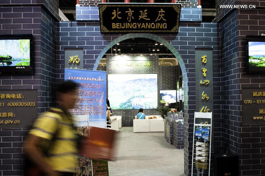 A visitor walks past the exhibition area of Beijing's Yanqing County at the Beijing International Tourism Expo (BITE) 2013 in Beijing, capital of China, June 21, 2013. The BITE 2013 kicked off on Friday, attracting 887 exhibitors from 81 countries and regions. (Xinhua/Liu Jinhai) 