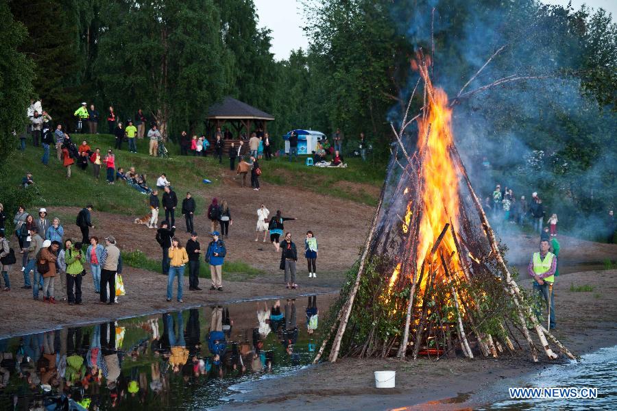 People gather around a bonfire to celebrate summer solstice in Lapland, north Finland in the Arctic Circle, in June 21, 2013. As Lapland situates in the Arctic Circle, there happens polar day in Summer solstice. Night and day the midnight sun stays above the horizon.(Xinhua/Yan Ting) 