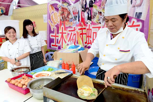 An exhibitor makes snacks at the Taiwan-themed temple fair in Xiamen, Fujian province, on Friday. More than 230 stands at the event were offering specialty products from Taiwan. After a new agreement was signed on Friday, the mainland will open 80 services sectors to Taiwan, while Taiwan will open 64 sectors to the mainland. Zhang Guojun / Xinhua