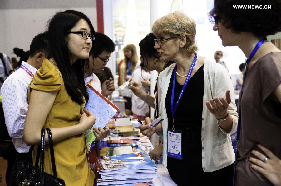 A visitor talks with a Russian exhibitor at the Beijing International Tourism Expo (BITE) 2013 in Beijing, capital of China, June 21, 2013. The BITE 2013 kicked off on Friday, attracting 887 exhibitors from 81 countries and regions. [Photo: Xinhua/Liu Jinhai] 