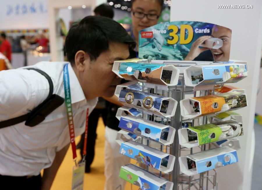 A visitor views 3D tourism souvenirs at the Beijing International Tourism Expo (BITE) 2013 in Beijing, capital of China, June 21, 2013. The BITE 2013 kicked off on Friday, attracting 887 exhibitors from 81 countries and regions. [Photo: Xinhua/Zhang Yu] 