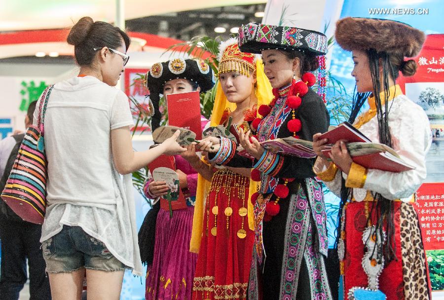Staff members wearing costumes of different ethnic groups are seen at the Beijing International Tourism Expo (BITE) 2013 in Beijing, capital of China, June 21, 2013. The BITE 2013 kicked off on Friday, attracting 887 exhibitors from 81 countries and regions. [Photo: Xinhua/Zhang Yu] 