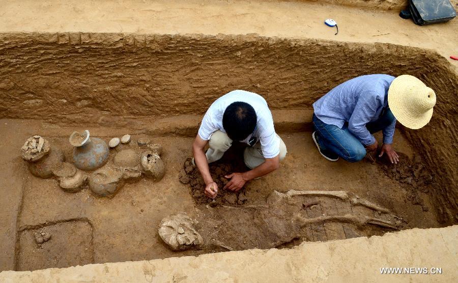 In this photo taken on June 8, 2013, archaeologists work at an ancient burial complex at Guxiang Township in Linying County, central China's Henan Province. Chinese archaeologists have discovered a well-reserved large burial complex dating back to the Warring States Period (475-221 BC) and the West Han (206 B.C.--25 AD.) Dynasty along the local section of the south-to-north water diversion project recently. Some 412 cultural relics have been unearthed in 119 excavated tombs. (Xinhua/Zhu Xiang) 