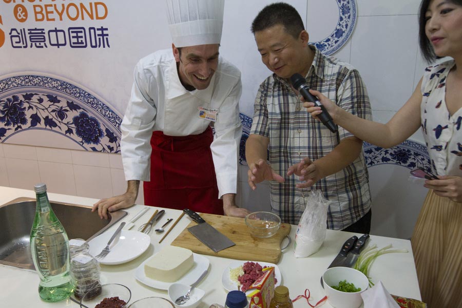Kiting Steven from Australia gets advice from the judge during the Chopsticks & Beyond Chinese Cooking Challenge on June 22, 2013. "Chopsticks and Beyond" is a Chinese cuisine challenge launched by CRIENGLISH.com to provide a platform for foreign food enthusiasts to show off their Chinese cooking skills and explore creative dishes with exotic flavor. It features China's four great traditions: Sichuan Cuisine, Cantonese Cuisine, Shandong Cuisine and Huaiyang Cuisine.(Xinhuanet/Yang Yi)