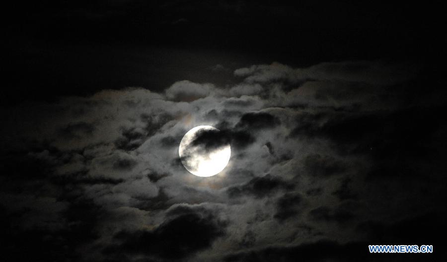 A full moon is seen surrounded by cloud in Haikou, capital of south China's Hainan Province, June 23, 2013. The moon looks 14 percent larger and 30 percent brighter than usual on Sunday. The scientific term for the phenomenon is "perigee moon", but it is also known as a "super moon". (Xinhua/Zhao Yingquan)