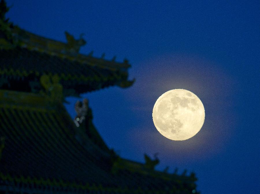 A full moon sets behind a building of the Forbidden City in Beijing, capital of China, June 23, 2013. The moon looks 14 percent larger and 30 percent brighter than usual on Sunday. The scientific term for the phenomenon is "perigee moon", but it is also known as a "super moon". (Xinhua/Chen Duo) 