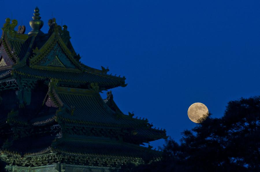 A full moon sets behind a building of the Forbidden City in Beijing, capital of China, June 23, 2013. The moon looks 14 percent larger and 30 percent brighter than usual on Sunday. The scientific term for the phenomenon is "perigee moon", but it is also known as a "super moon". (Xinhua/Chen Duo) 