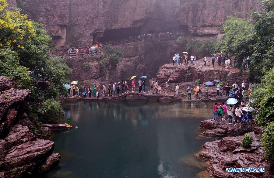 Tourists stroll in the Hongshixia scenic resort of Yuntai Mountain in Xiuwu County of central China's Henan Province, June 22, 2013. (Xinhua/Zhao Peng)