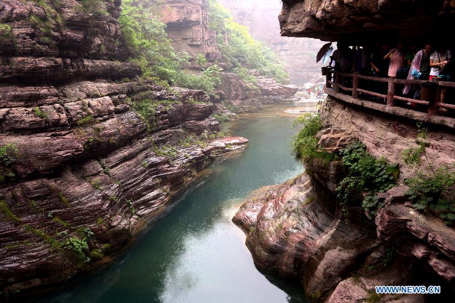 Tourists stroll in the Hongshixia scenic resort of Yuntai Mountain in Xiuwu County of central China's Henan Province, June 22, 2013. (Xinhua/Zhao Peng)