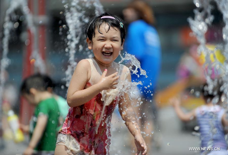 A child frolics at a fountain in Shenyang, capital of northeast China's Liaoning Province, June 23, 2013. (Xinhua/Zhang Wenkui)