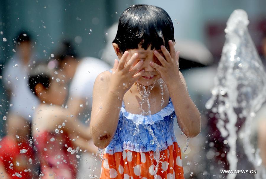 A child frolics at a fountain in Shenyang, capital of northeast China's Liaoning Province, June 23, 2013. (Xinhua/Zhang Wenkui)