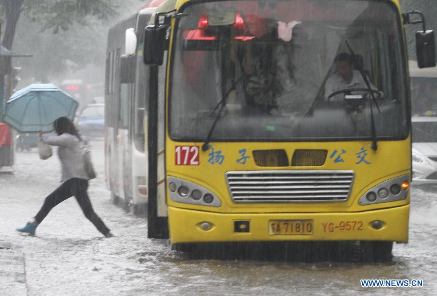 A woman gets off the bus in the rain on the street in Nanjing, capital of east China's Jiangsu Province, June 23, 2013. (Xinhua/Dong Jinlin) 