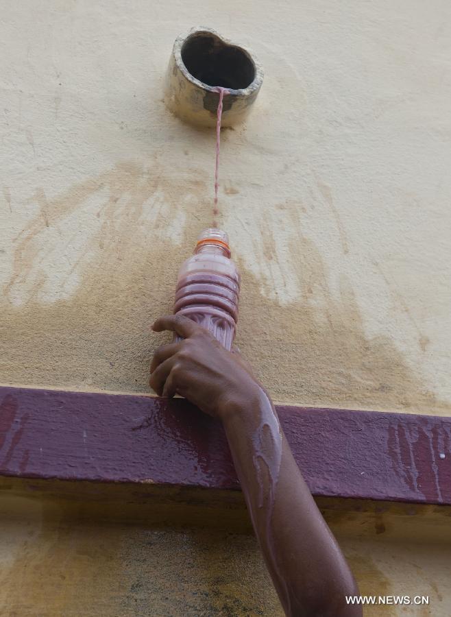 An Indian boy collects milk and water during the holy bathing ceremony of Lord Jagannath at a temple near Calcutta, capital of eastern Indian state West Bengal, on June 23, 2013. (Xinhua/Tumpa Mondal) 