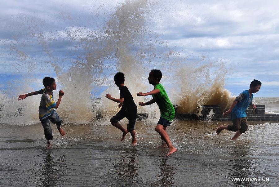 Children play with water as huge wave hit the beachside of Leshan Village in Fangchenggang City, south China's Guangxi Zhuang Autonomous Region, June 23, 2013. The tropical storm Bebinca has brought strong rain to Guangxi. (Xinhua/Liang Zongyang)  